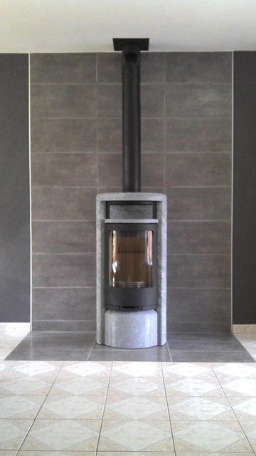 Poêle à bois gris et noir devant un mur sombre