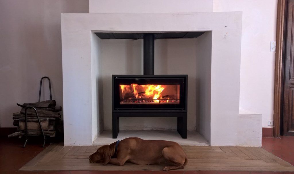 Poêle à bois de forme carré aménagé dans un ancien espace de foyer de cheminée