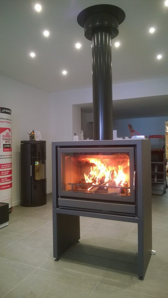 Poêle à bois de forme rectangulaire au milieu d'un salon avec foyer allumé