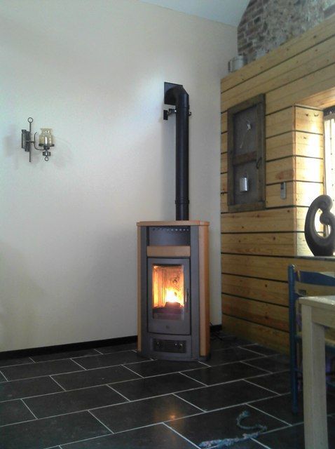 Poêle à pellets de couleur marron avec foyer allumé et carrelage noir