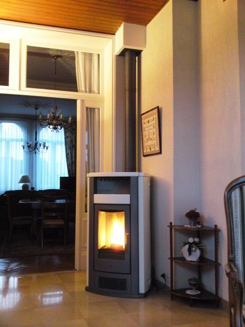 Poêle à pellets de couleur noir dans le coin d'une pièce avec foyer allumé