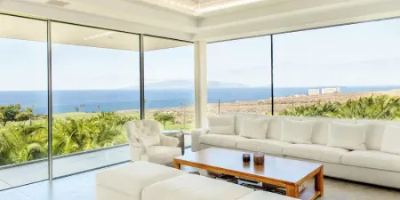 Una sala de estar con muchas ventanas y vista al mar.