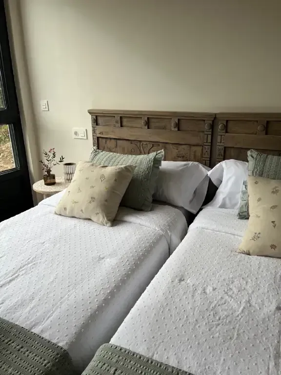 Dos camas con ropa de cama blanca, almohadas y cabecero rústico de madera.