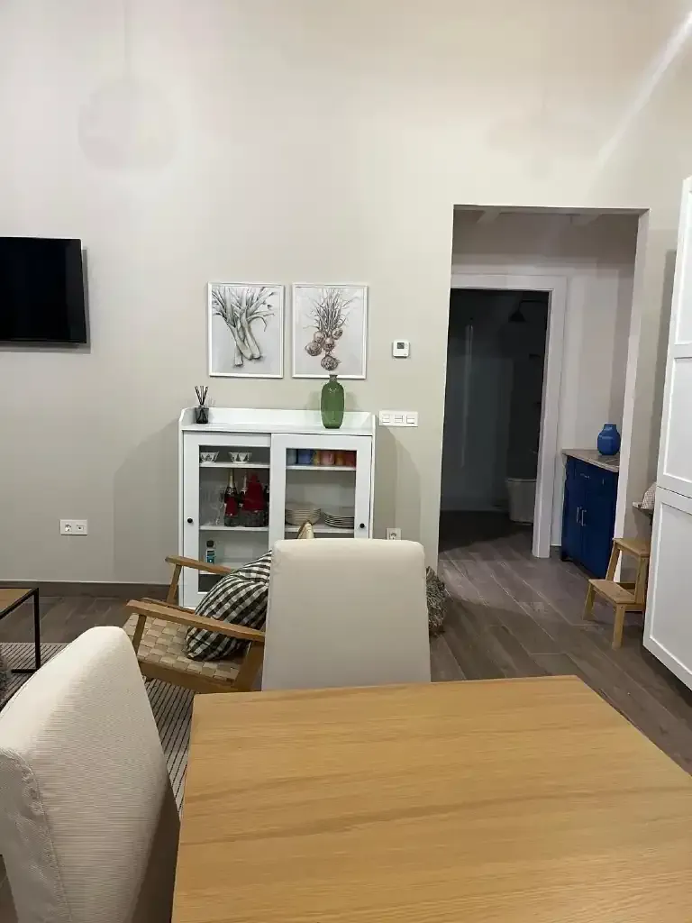 Sala de estar con mueble blanco, arte, puerta y mesa de madera.