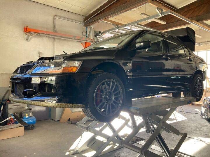 Un'auto nera, una Mitsubishi Lancer Evolution, su un ponte sollevatore in un garage
