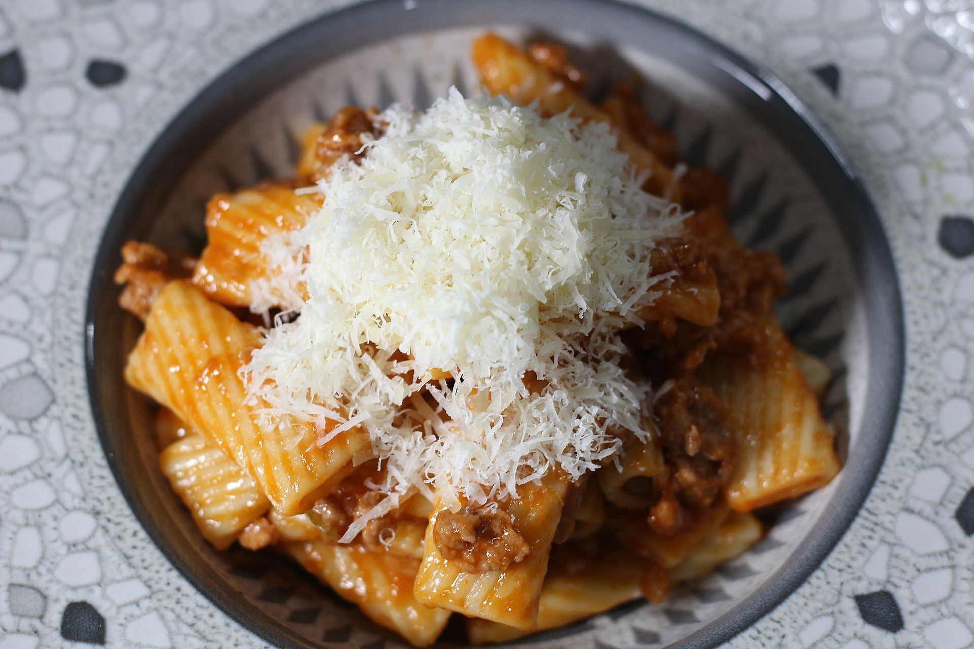 Pasta Rigatoni con salsa de carne y queso rallado en un bol.