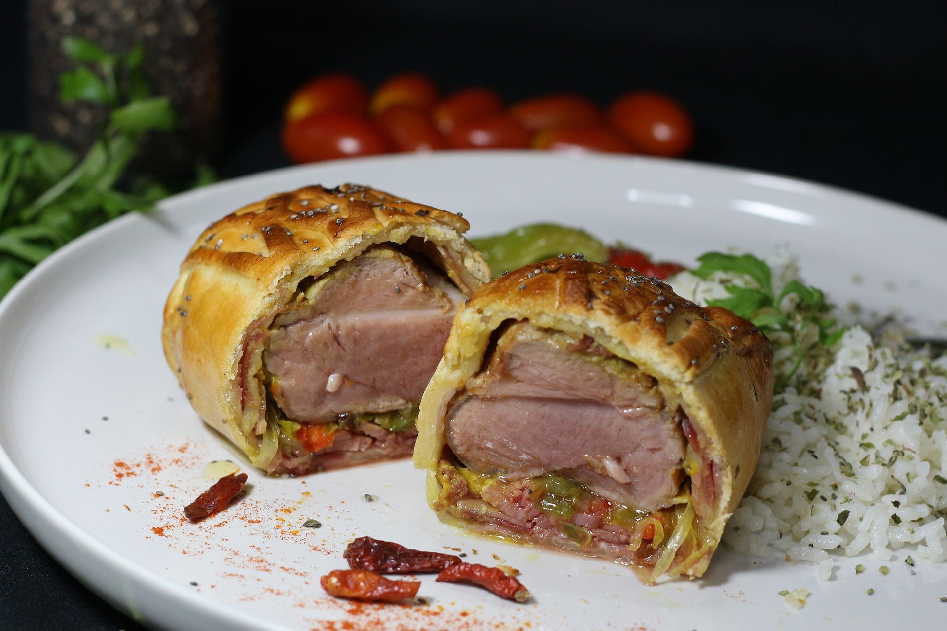 Dos mitades de un plato de carne al horno con costra de hojaldre en un plato blanco, servido con arroz.