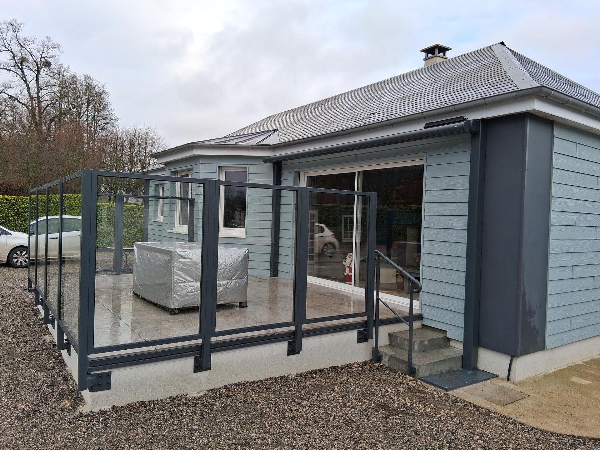 Petite maison grise avec une véranda vitrée et une rampe d’accès, en construction