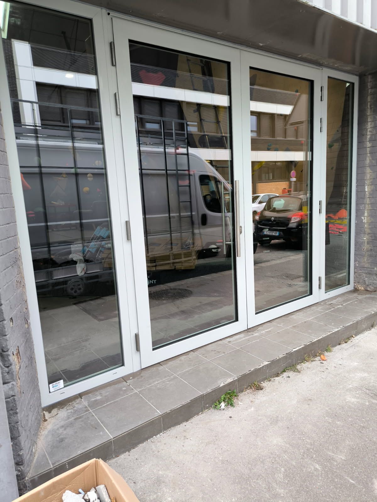 Vitrine avec des portes à cadre blanc reflétant une camionnette dans la rue