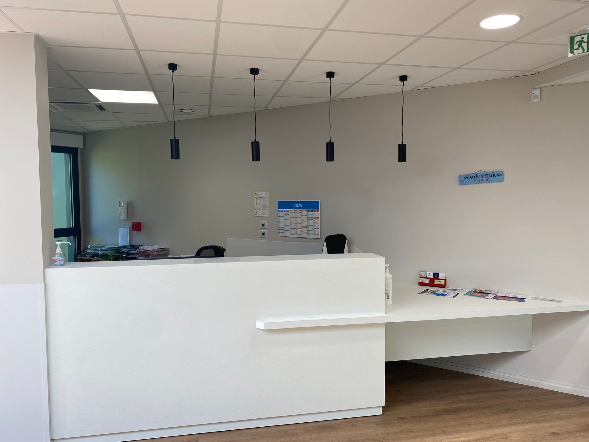Comptoir d’accueil blanc moderne dans le hall lumineux d’un bureau, avec des suspensions lumineuses