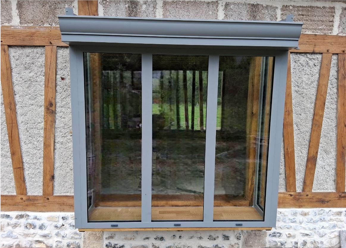 Ensemble de fenêtre coulissante en verre intégré dans un mur de brique et de bois avec des moulures grises