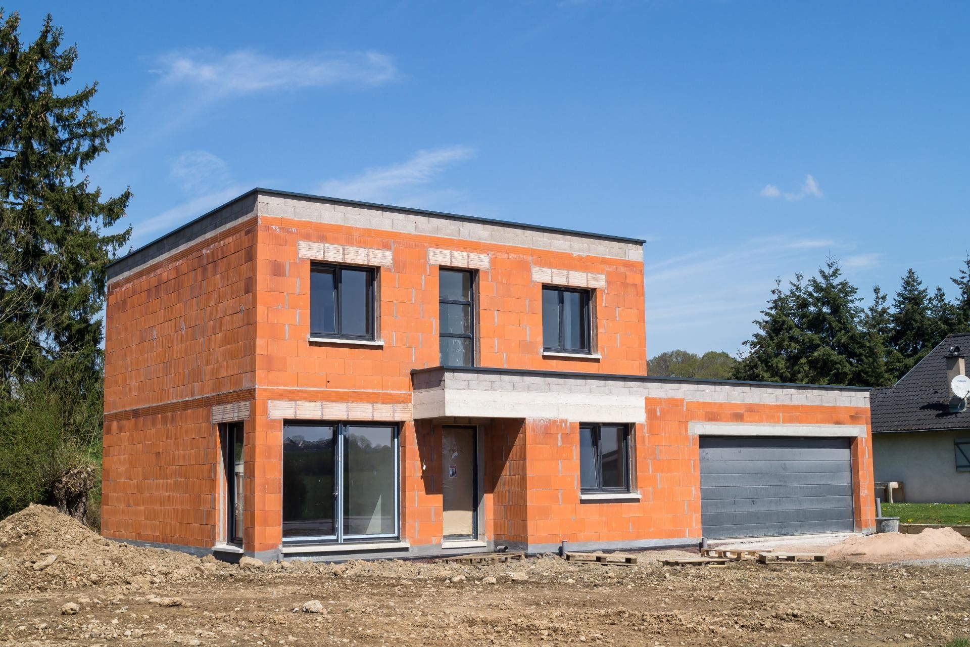 Auf einem Feld wird ein Backsteinhaus gebaut.