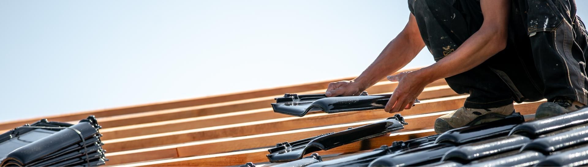 Ein Dachdecker beim Verlegen von Dachziegeln.