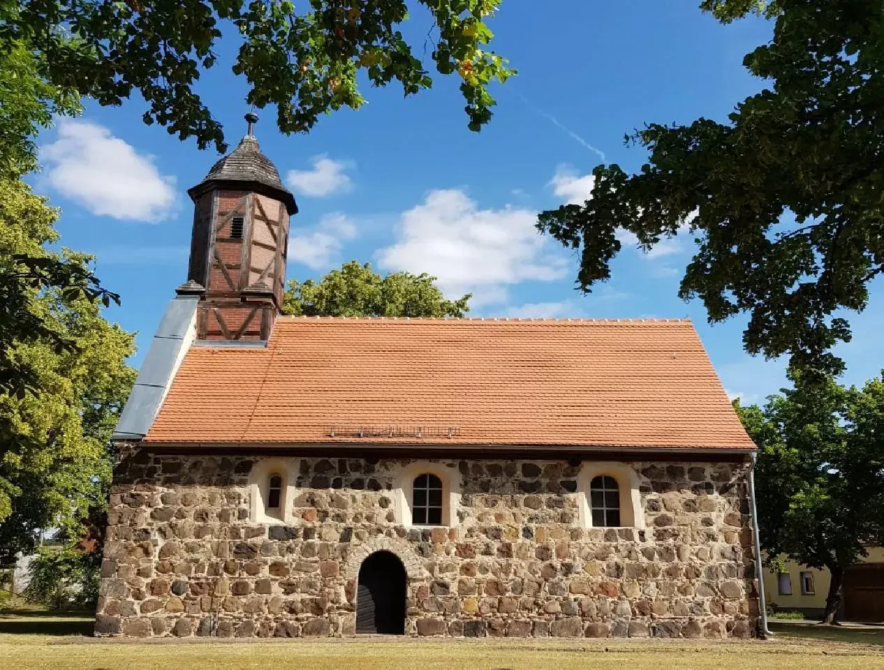 Eine kleine Steinkirche mit einem roten Ziegeldach und einem kleinen Glockenturm.