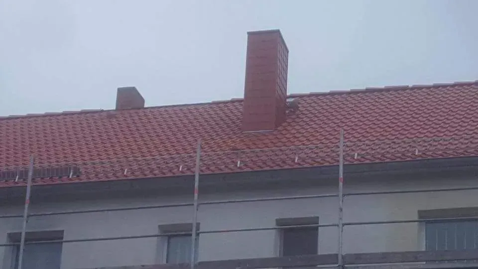 Ein neu gedecktes rotes Ziegeldach und einem Schornstein.