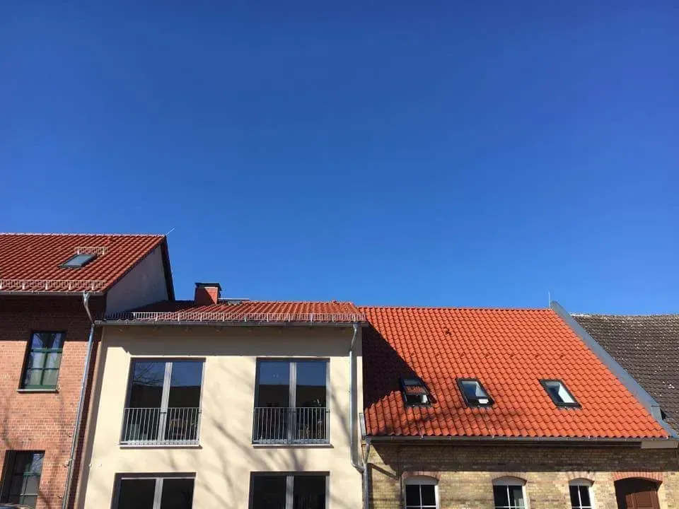 Ein Gebäude mit einem neu gedeckten roten Ziegeldach und Schneefanggittern.