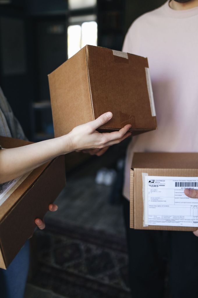 Manos intercambiando una caja de cartón marrón durante una entrega en interiores