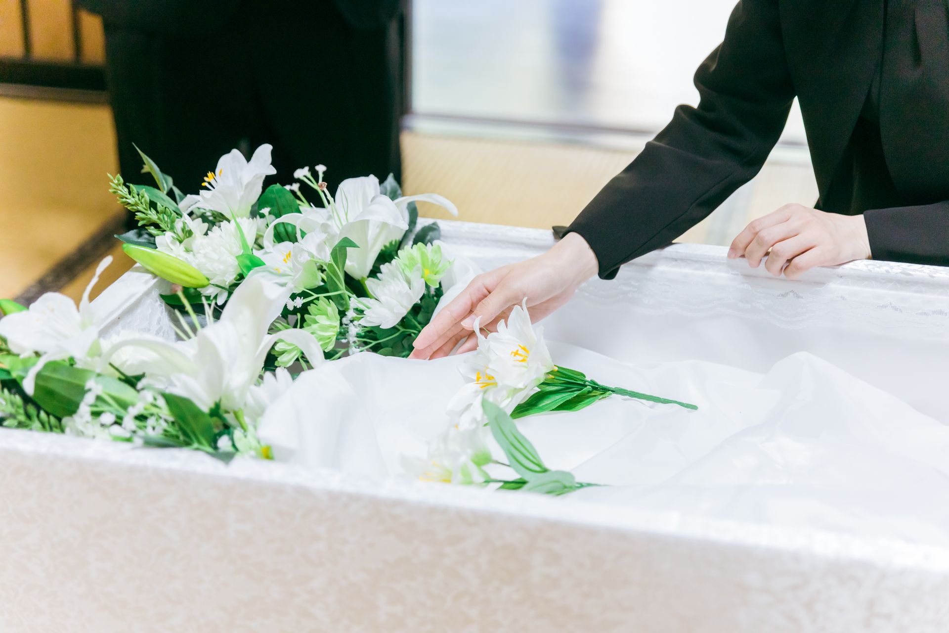 Une femme pose une fleur dans un cercueil ouvert