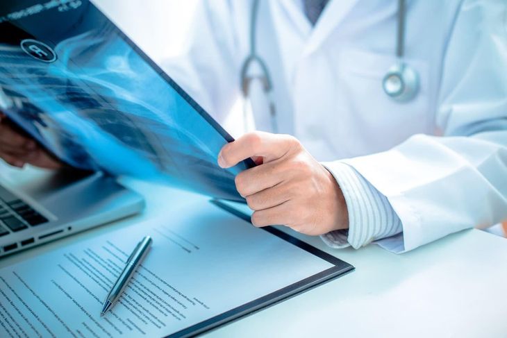 Un médico examina una radiografía en un escritorio con un estetoscopio y documentos cerca.