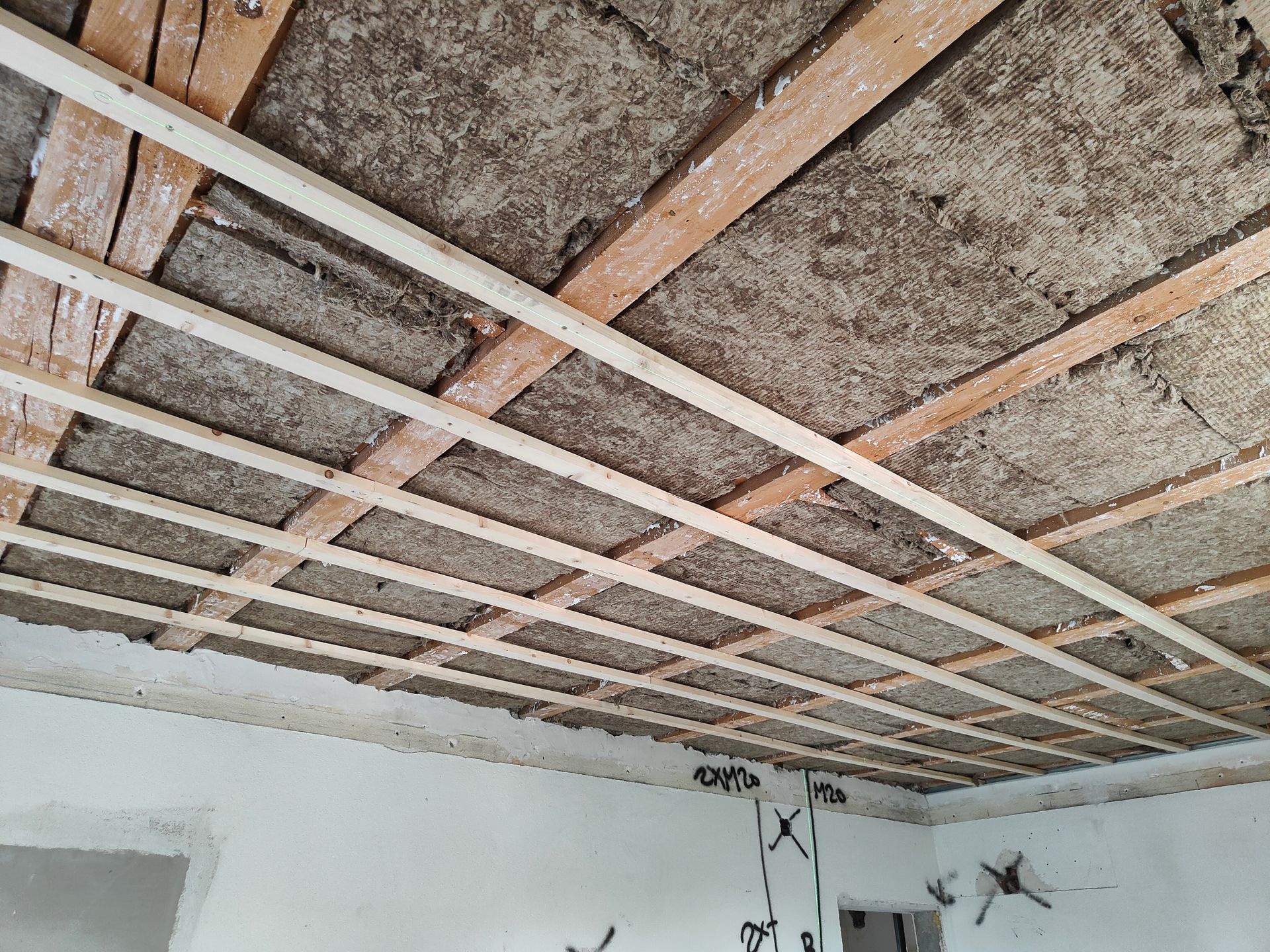 Eine Person mit behandschuhter Hand beizt Holzplanken mit einer Farbrolle.