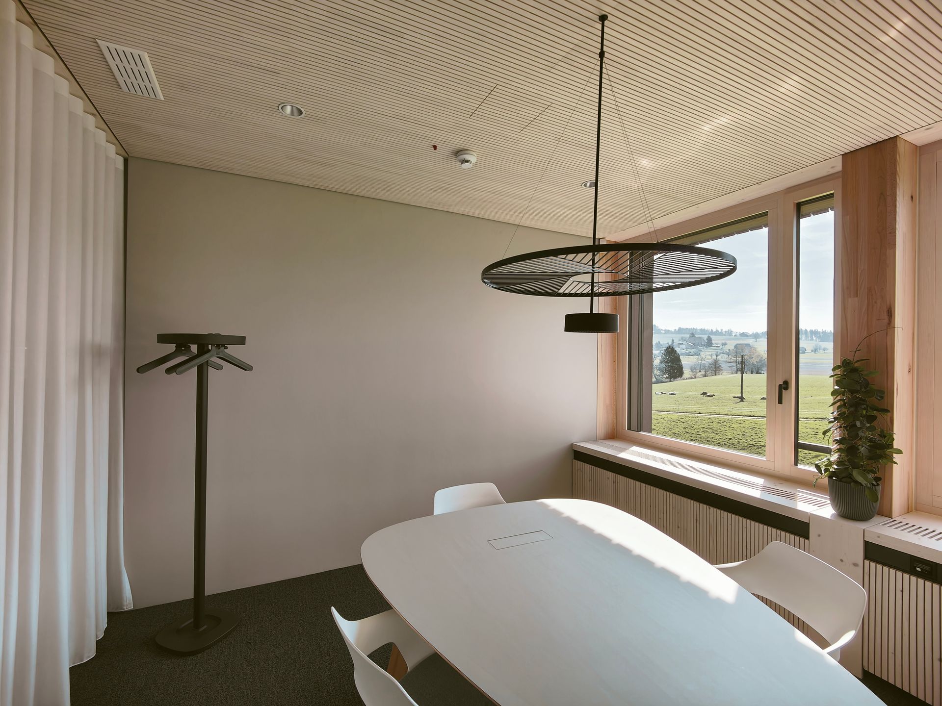 Eine Person montiert Gipskartonplatten an einem Metallgitterdeckenrahmen in der Nähe eines Fensters.