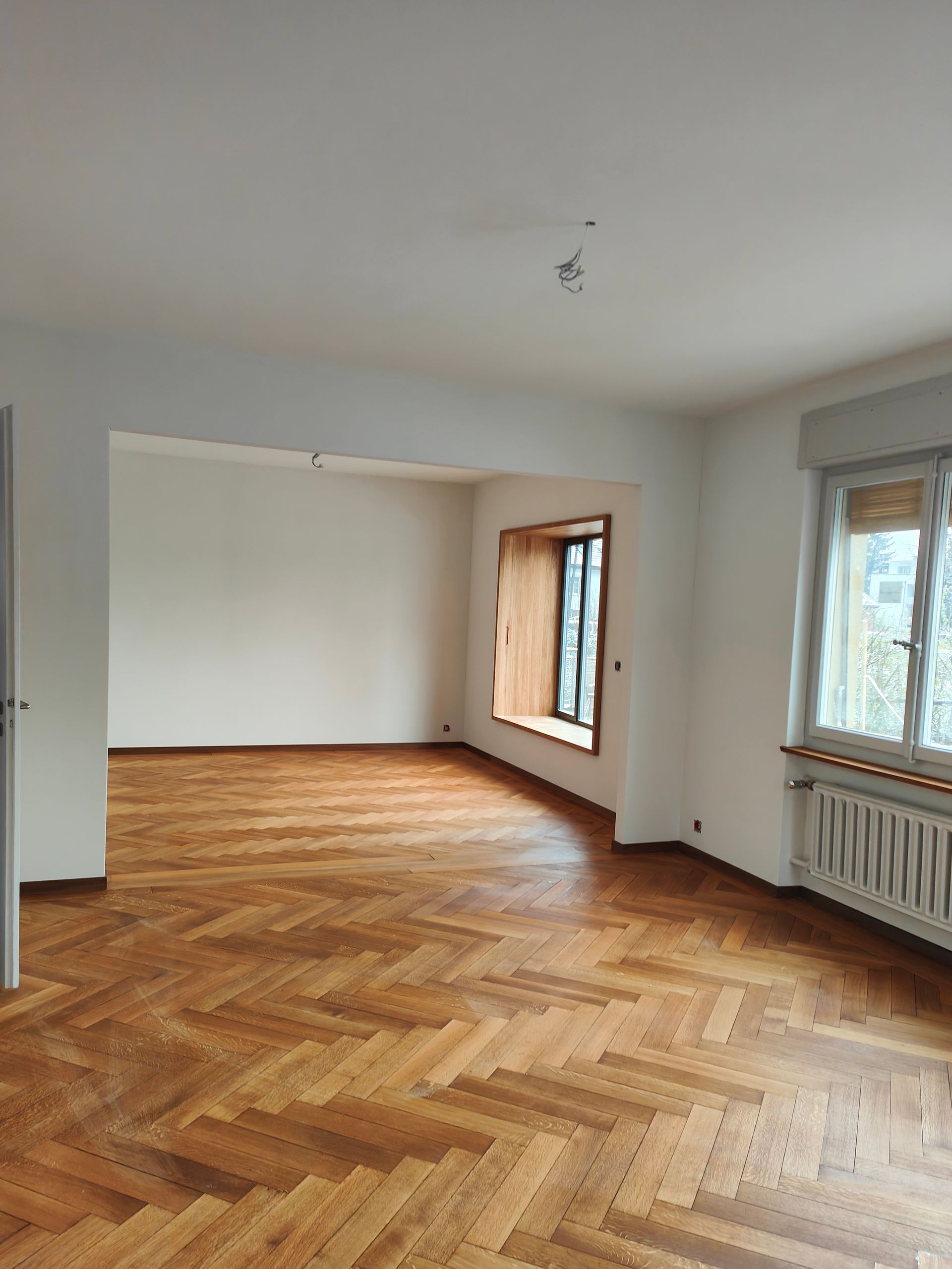 Eine Person glättet mit einer Kelle grauen Zement an einer Wand.