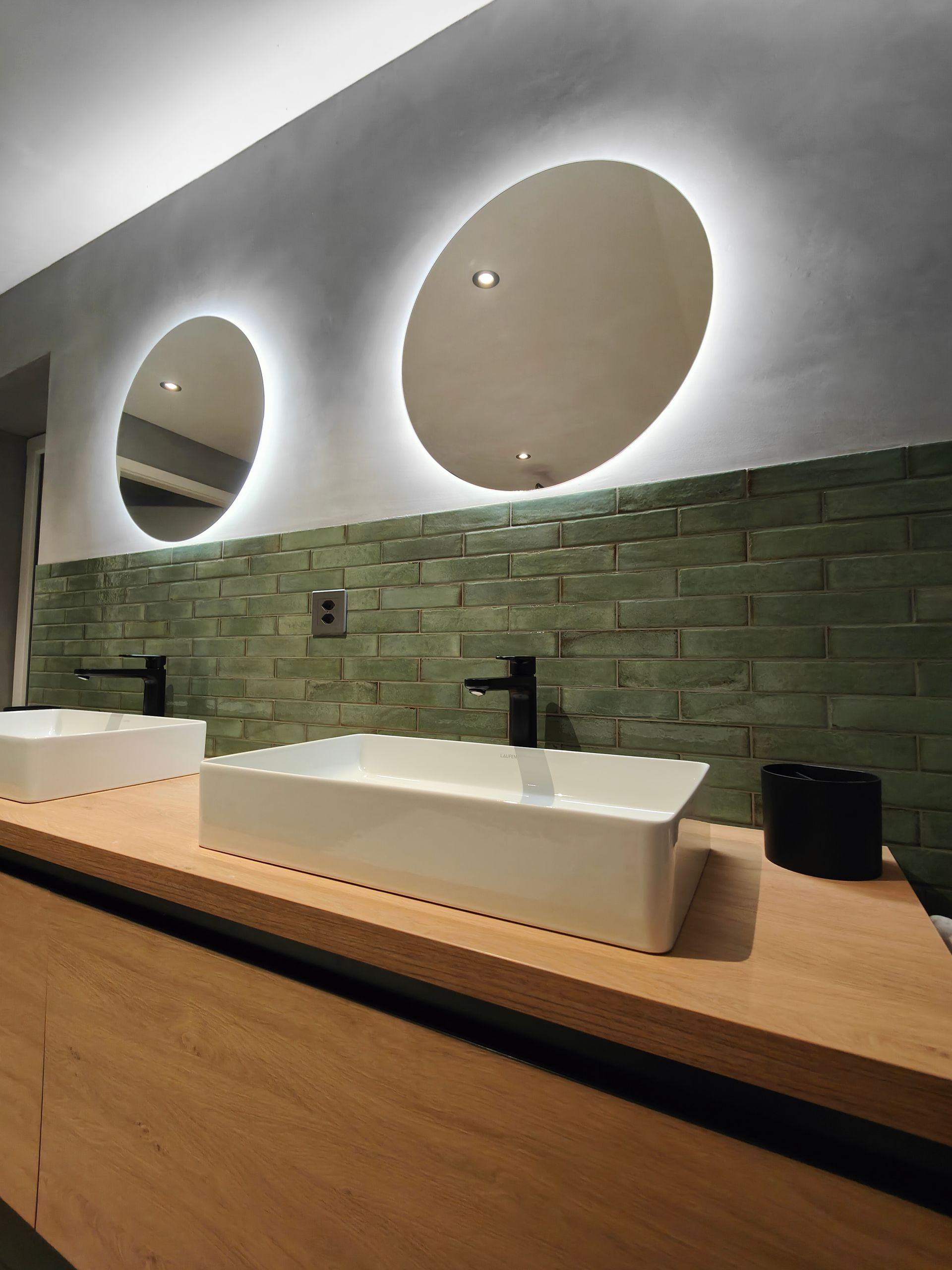 Ein Mann installiert auf einer Leiter elektrische Leitungen in einem Raum; Gipskarton- und Ziegelwand sind sichtbar.