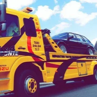 Une dépanneuse jaune transportant une voiture noire sous un ciel bleu.