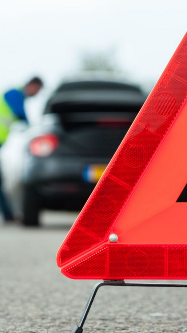 Un triangle de signalisation d'arrêt de voiture et une voiture noire floutée