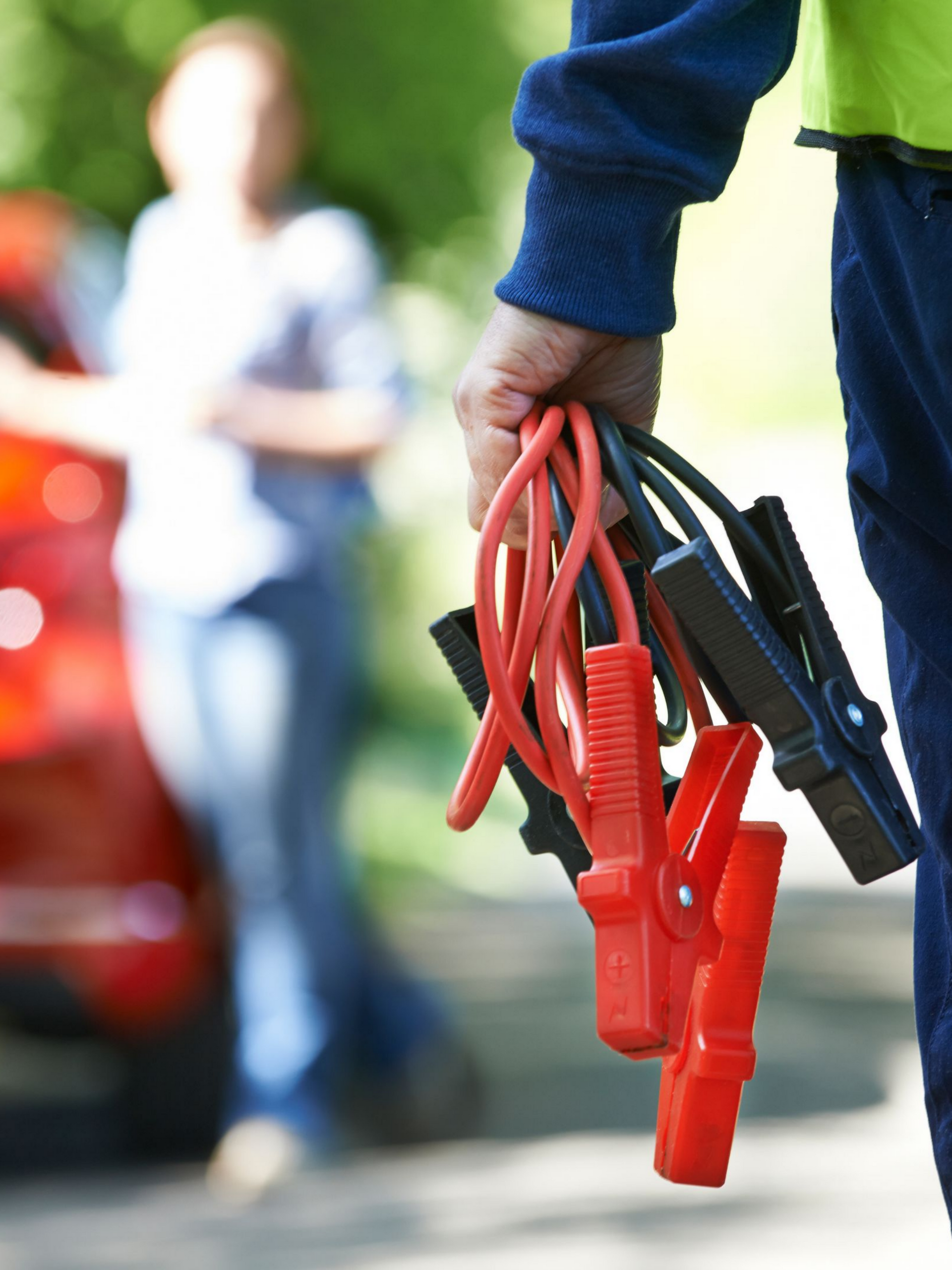 Personne tenant des câbles de démarrage, prête à aider quelqu'un avec un problème de voiture.