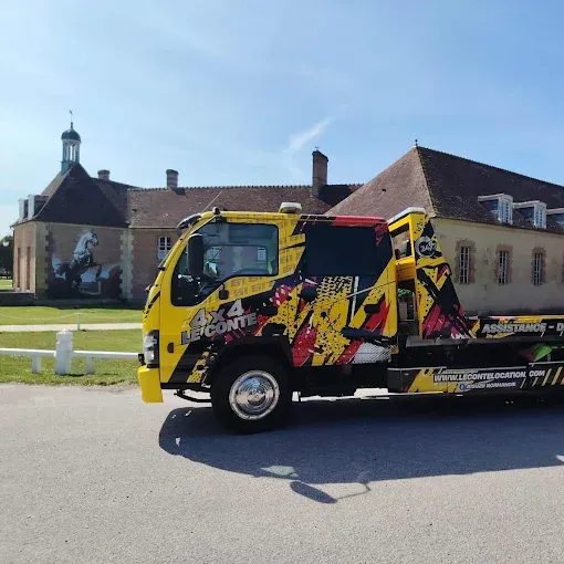 Dépanneuse jaune devant un bâtiment avec une tourelle par une journée ensoleillée.