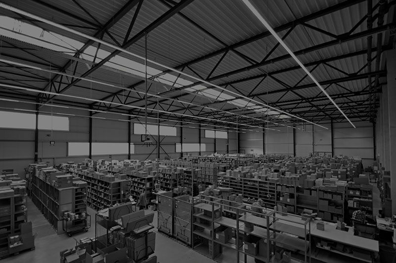 Ein Schwarzweißfoto einer großen Lagerhalle mit zahlreichen Regalen.