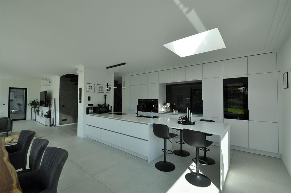 Eine Küche mit weißen Schränken und schwarzen Hockern