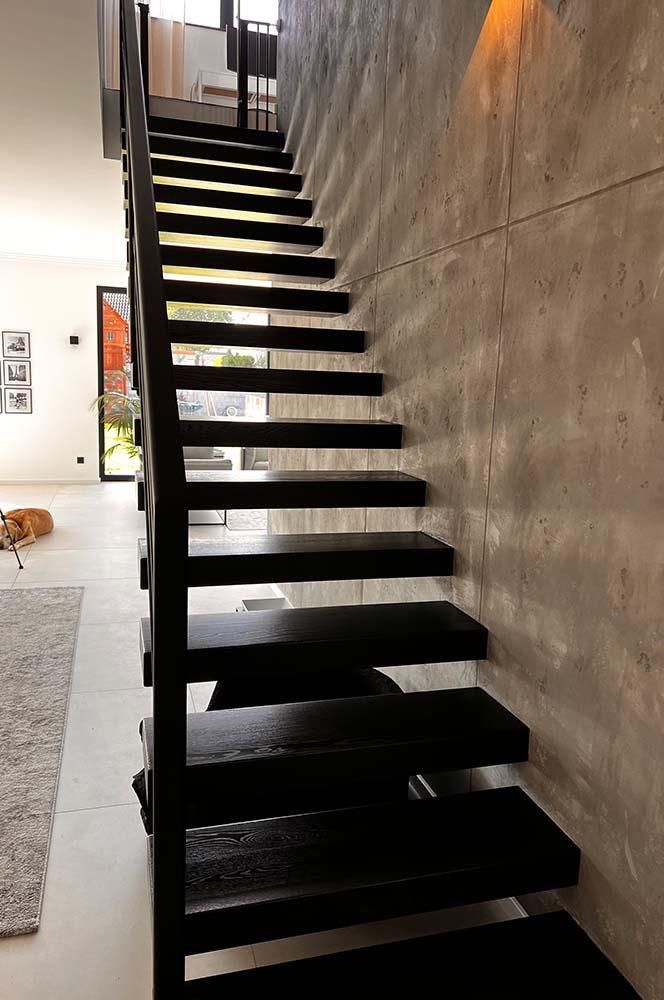 Eine schwarze Treppe mit einer Betonwand dahinter
