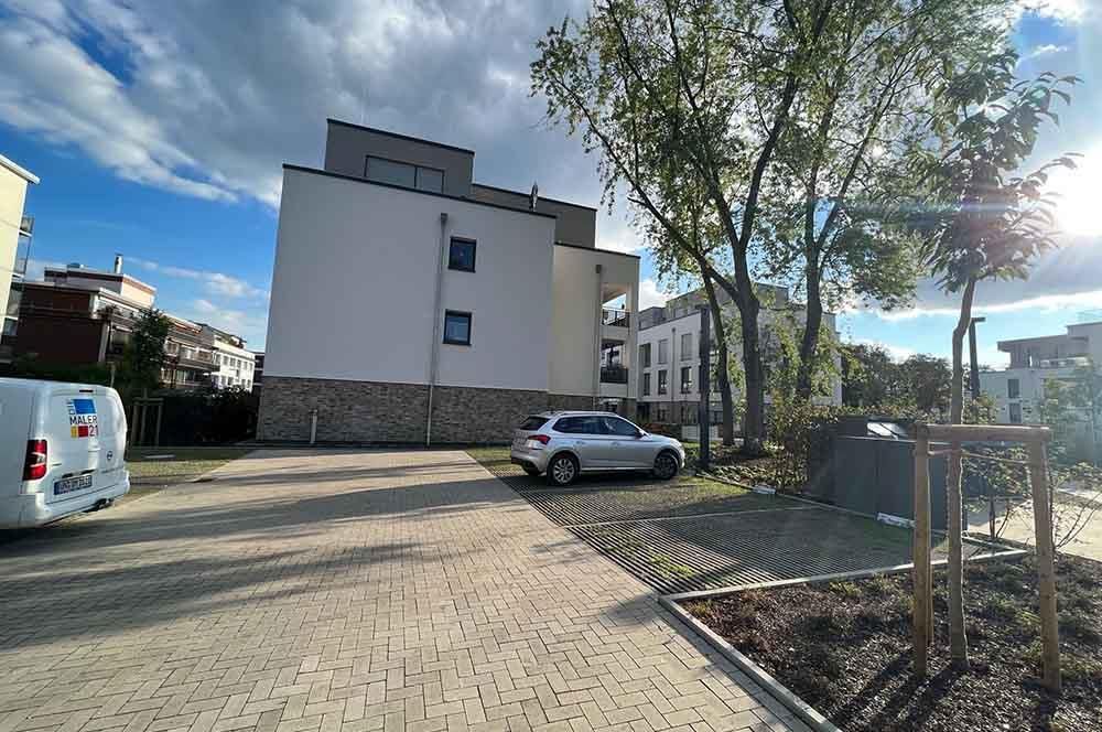 Ein weißer Lieferwagen steht auf einem Parkplatz vor einem Gebäude.