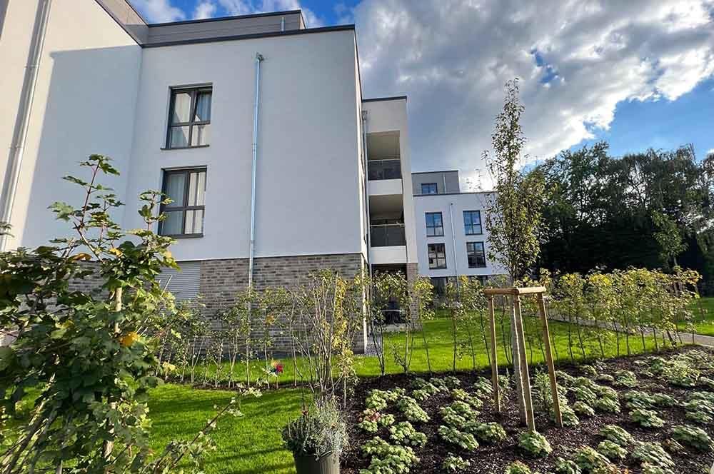 Ein großes weißes Gebäude mit vielen Fenstern und Bäumen davor