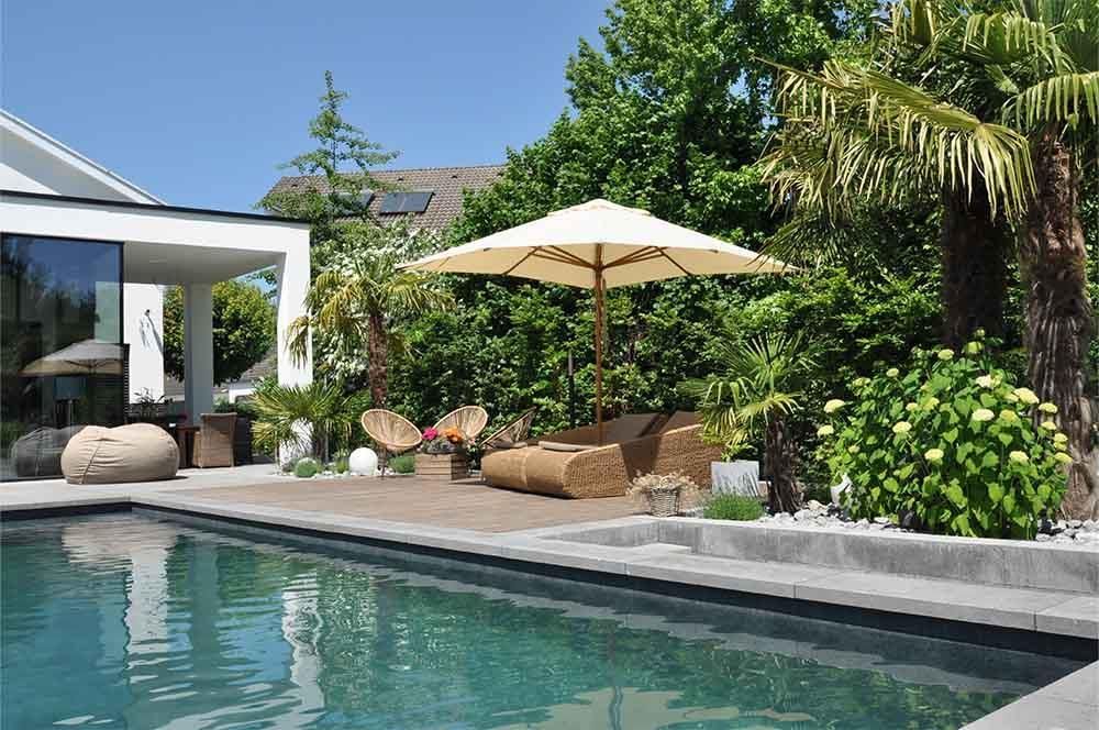 Ein Swimmingpool mit einem weißen Sonnenschirm vor einem Haus