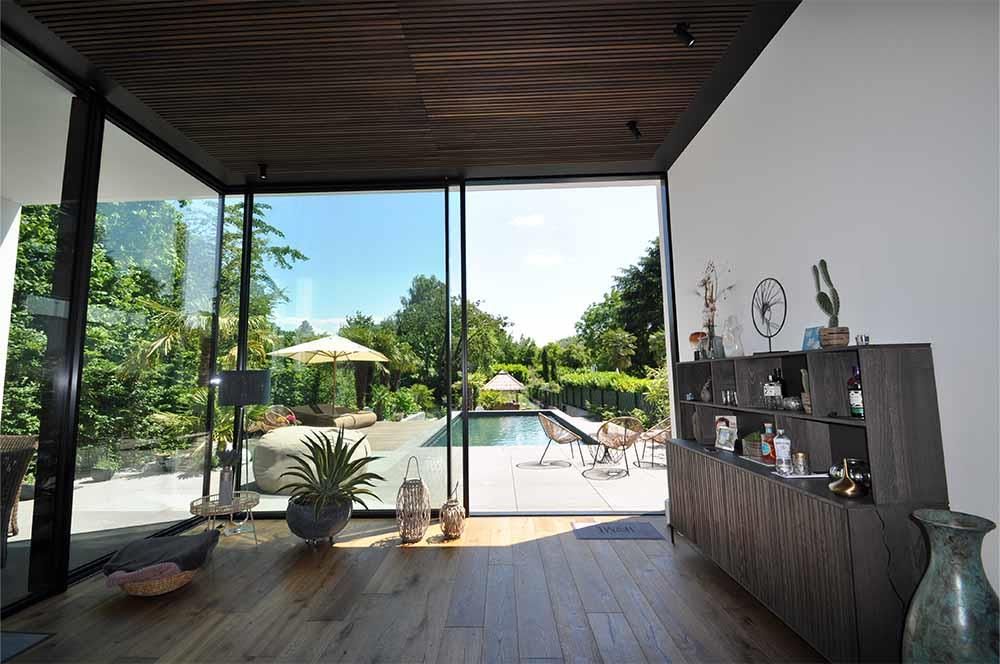 Ein Wohnzimmer mit einer Glasschiebetür, die zu einem Swimmingpool führt