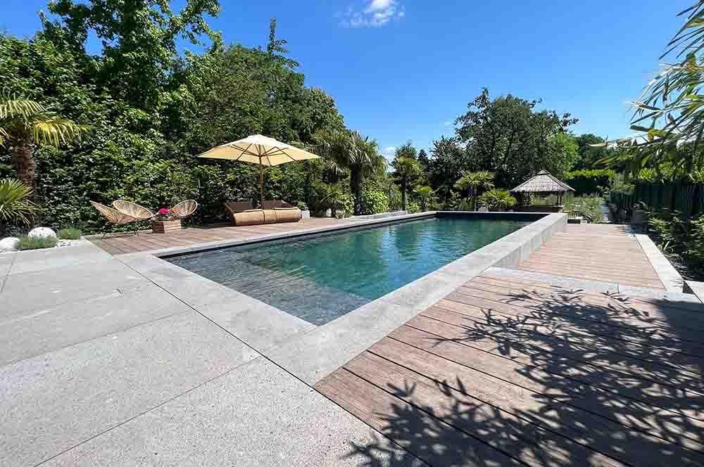 Ein großer Swimmingpool ist von Bäumen und einem Holzdeck umgeben.