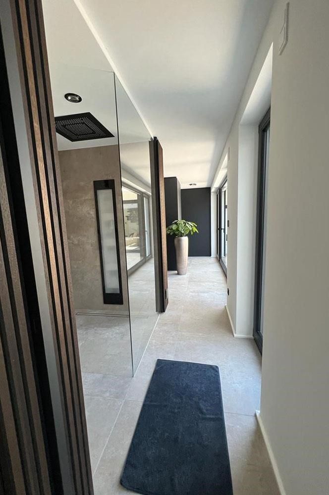 Ein langer Flur mit einem schwarzen Teppich und einem Spiegel an der Wand.