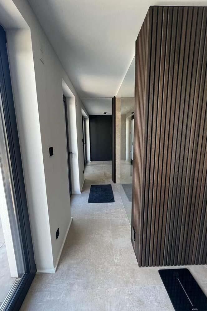 Ein Flur in einem Haus mit einer Holzwand und einer schwarzen Tür.