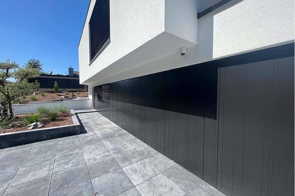 Ein schwarz-weißes Gebäude mit einer Terrasse davor