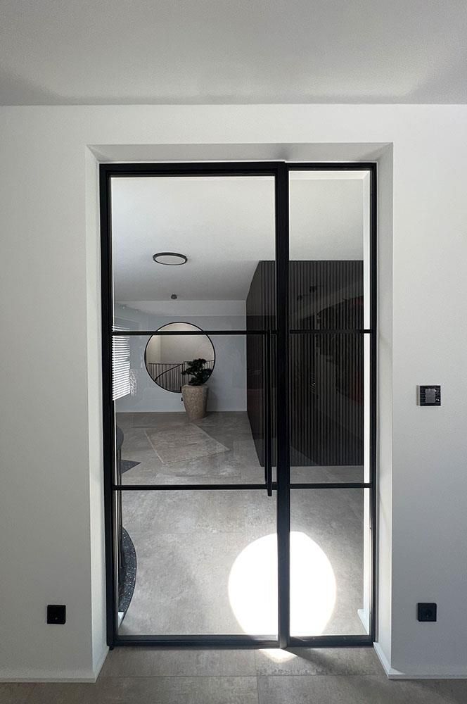 Eine Tür mit schwarzem Rahmen führt zu einem Wohnzimmer.