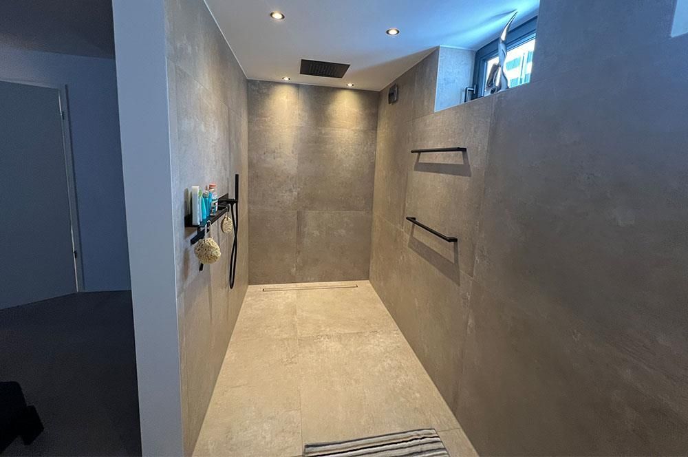 Ein Badezimmer mit ebenerdiger Dusche und einem Teppich auf dem Boden