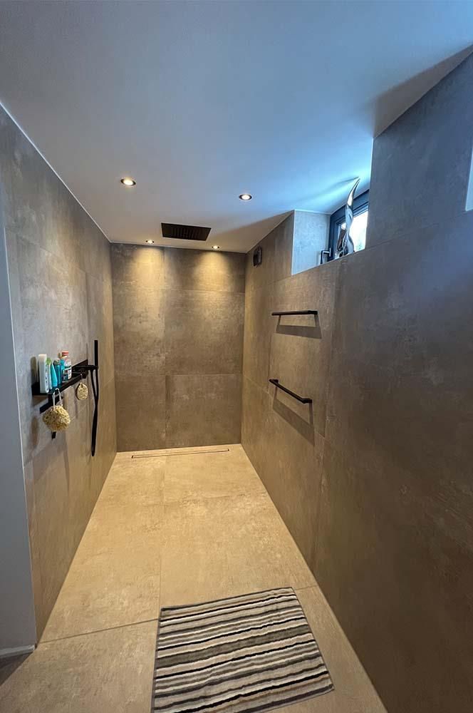 Ein Badezimmer mit ebenerdiger Dusche und einem Teppich auf dem Boden.