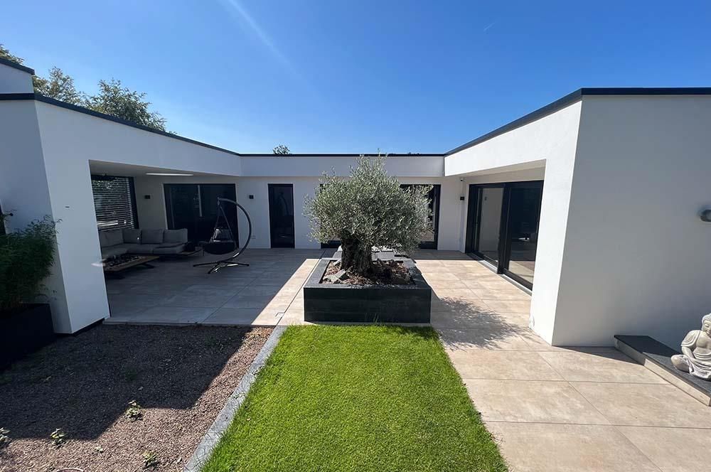 Ein weißes Haus mit einer Terrasse und einem Baum davor