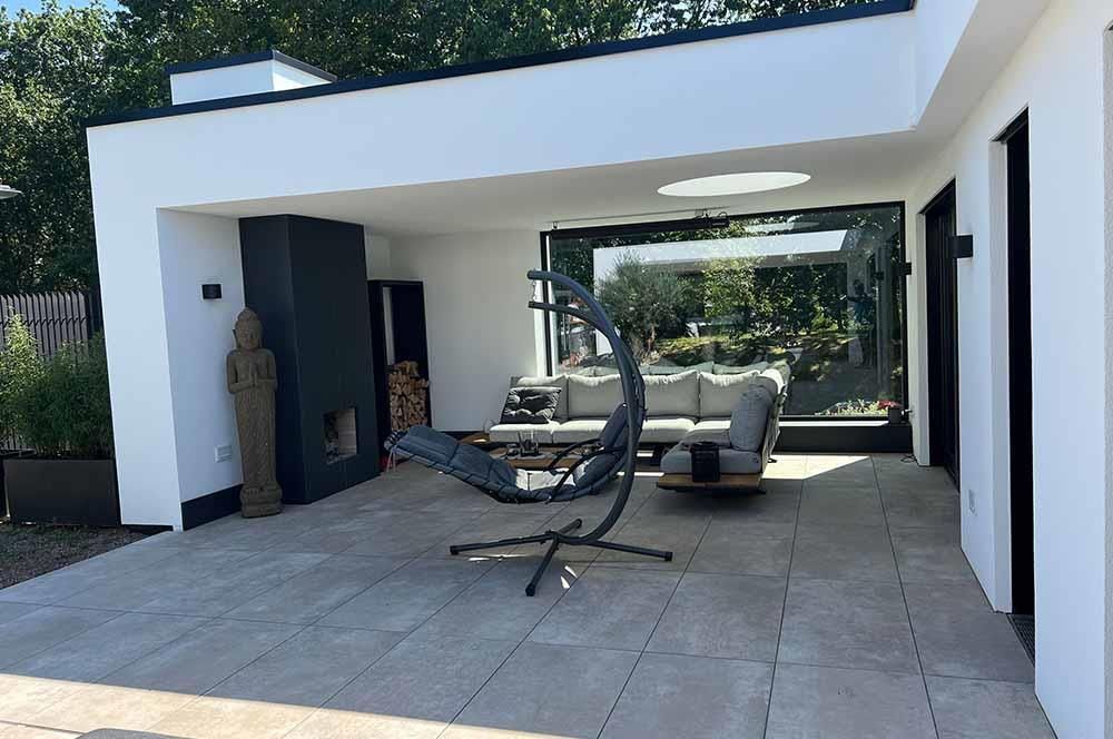 Eine Terrasse mit Sofa und Sessel vor einem Haus