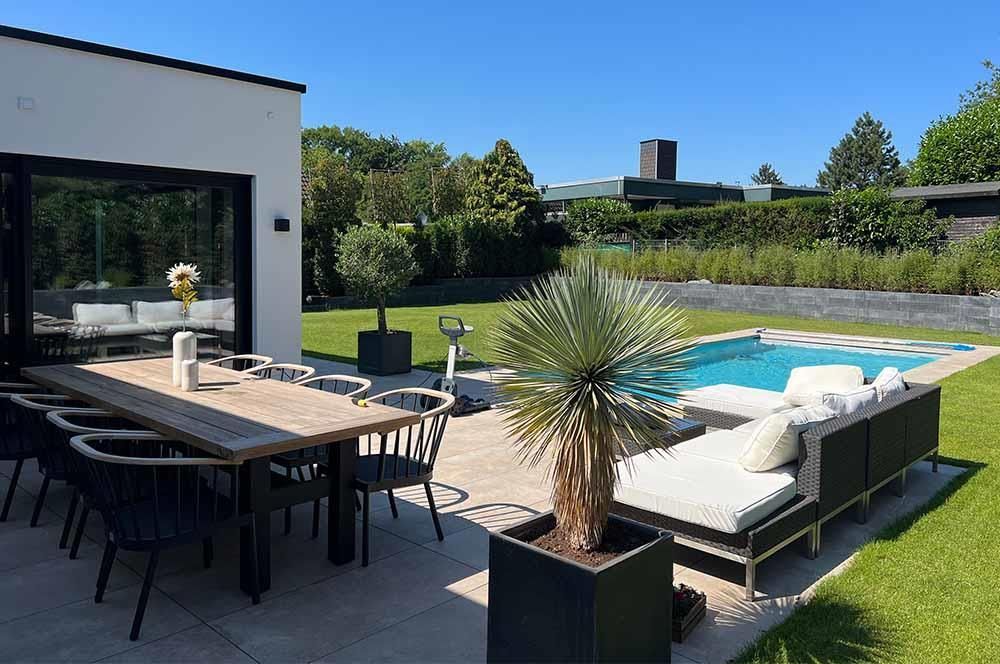 Eine Terrasse mit Tisch und Stühlen neben einem Swimmingpool