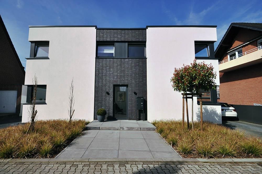 Ein weißes Haus mit einem Backsteingebäude im Hintergrund