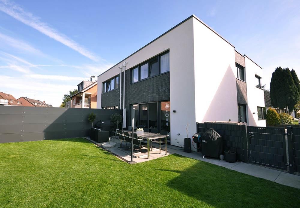 Ein großes weißes Haus mit einem schwarzen Zaun darum herum